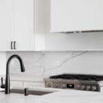 An,All,White,Kitchen,With,A,Black,Faucet,On,A